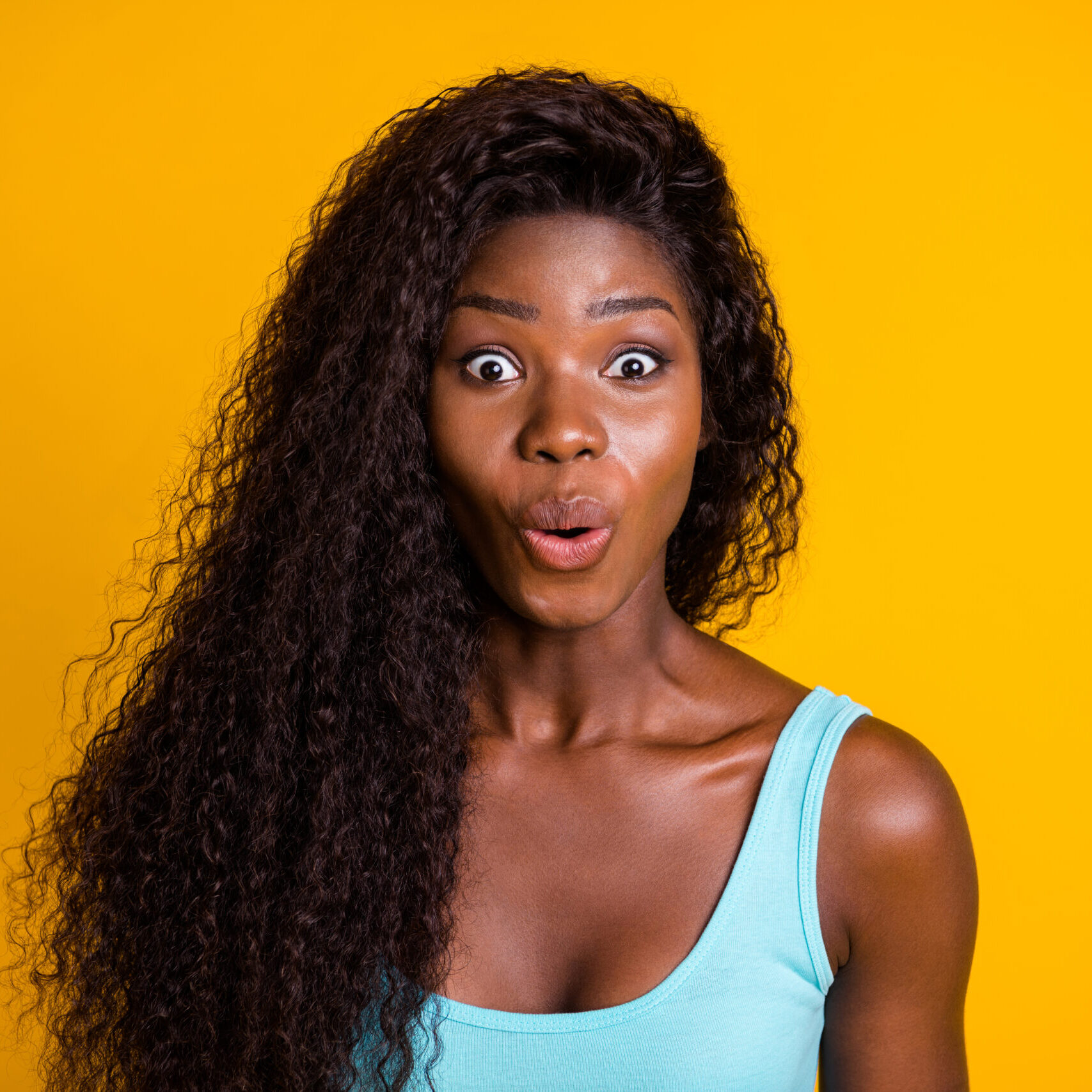 Photo portrait of surprised african american woman wearing blue singlet isolated on vivid yellow colored background